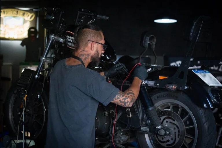 Paulinho fazendo a manutenção elétrica de uma motocicleta Harley-Davidson na oficina Brazil Motos